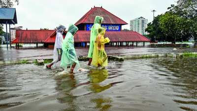 children walk past sree mahadeva temple in kochi on saturday eight deaths were reported as heavy rain lashed several parts of kerala idukki kottayam and pathanamthitta were the worst hit